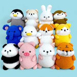 Może przedstawiać: Kolekcja 12 pluszowych zabawek wykonanych na szydełku, w tym panda, świnka, pingwin, słoń, tygrys, kot, królik i wiele innych. Zwierzęta są w różnych kolorach i mają urocze buźki.