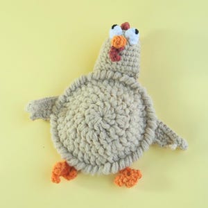 May include: A handmade crochet turkey toy in shades of beige, orange, and white. The turkey has a textured body, outstretched wings, and orange feet. The head features white eyes with black pupils, an orange wattle, and a red snood.