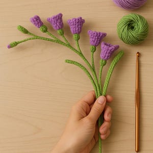 May include: A handmade crochet flower bouquet with purple bell-shaped blooms and green stems. A ball of purple yarn, a ball of green yarn, and a crochet hook are also visible.