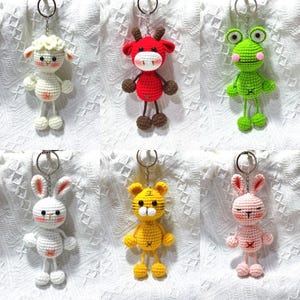 May include: A set of ten crocheted animal keychains. The animals include a sheep, cow, frog, rabbit, and tiger. Each keychain is made with different colored yarn and has a small key ring attached.