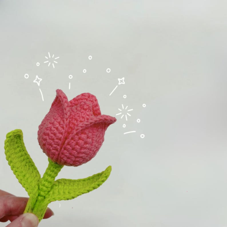 K&ouml;nnte beinhalten: Eine rosa geh&auml;kelte Tulpe mit gr&uuml;nen geh&auml;kelten Bl&auml;ttern. Die Tulpe ist ein handgemachtes Handwerk.
