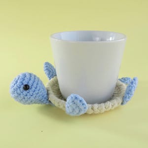May include: A set of three ceramic mugs with a speckled, matte finish. The mugs are in shades of blue, green, and white. Each mug has a simple, modern design, perfect for coffee or tea. The mugs are stacked on top of each other.
