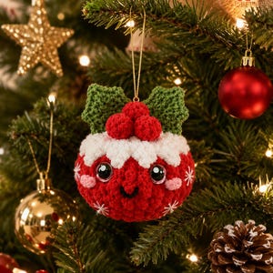 Peut inclure: Une d&eacute;coration de No&euml;l ronde en crochet rouge avec un sommet blanc ressemblant &agrave; du gla&ccedil;age, trois petites baies rouges et deux feuilles vertes. L'ornement pr&eacute;sente un visage souriant avec de grands yeux noirs, des joues roses et des flocons blancs.