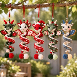 May include: Five crocheted dragon ornaments hanging from a branch. Each features a spiral body, small wings, and a hanging loop. The dragons are colored in combinations of red, white, green, and blue, accented with small beads and pom-poms.