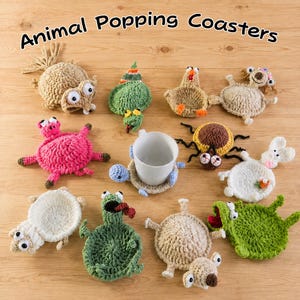 May include: A collection of crocheted animal coasters with the text "Animal Popping Coasters" at the top. The set includes various creatures like a pink pig, green frog, brown spider, and white rabbit, with one coaster supporting a white mug.