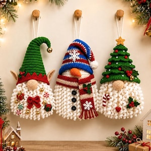 May include: Three hanging crochet ornaments featuring a gnome with a green hat, a snowman with a blue striped hat and scarf, and a gnome with a green Christmas tree hat. Each figure has a white curly beard, decorative buttons, and festive accents.
