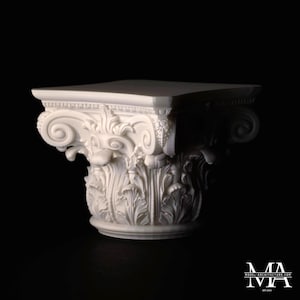 Peut inclure: Un chapiteau de colonne architecturale blanc, finement sculpté, avec un dessus carré et des détails ornés de volutes et de feuilles. Le chapiteau est de conception classique, probablement à des fins décoratives. Le fond est noir.