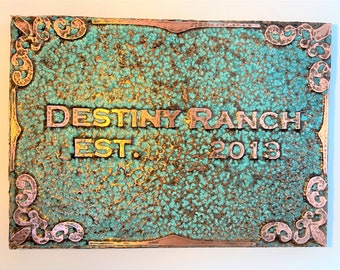May include: A rustic copper sign with a turquoise patina and ornate scrollwork. The sign reads "Destiny Ranch Est. 2013".
