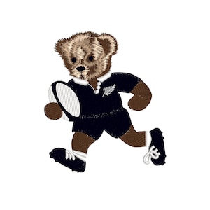 May include: A brown teddy bear wearing a black rugby jersey with a white fern design, holding a white rugby ball and running.