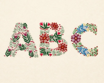 May include: The letters A, B, and C are rendered in embroidery on a cream fabric. Each letter is composed of intricate floral patterns featuring red, pink, and blue flowers, green leaves, and small red berries, creating a botanical alphabet design.