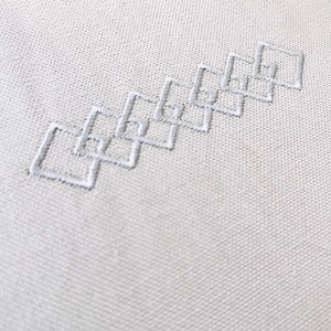 May include: White fabric with a pattern of white embroidered diamonds.