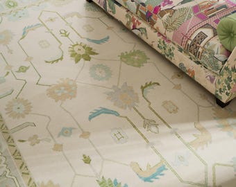 May include: A white rug with a light green, blue, and beige floral pattern. The rug has a subtle geometric design.