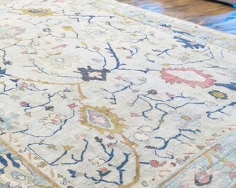 May include: A light blue rug with a floral pattern in shades of blue, pink, and gold. The rug has a traditional Persian design with intricate details.
