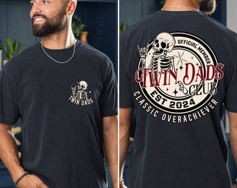 Könnte beinhalten: Schwarzes T-Shirt mit einer weißen Grafik eines Skeletts mit dem Text "Twin Dads Club Est 2024 Classic Overachiever Official Member" auf der Rückseite und einer kleineren Grafik eines Skeletts mit dem Text "Twin Dads" auf der Vorderseite.