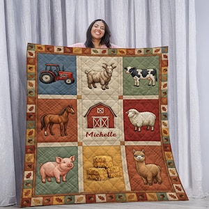 May include: A personalized farm-themed quilt featuring a red tractor, goat, cow, horse, sheep, pig, hay bales, and an alpaca. The quilt has a barn in the center with the name "Michelle" below it. The quilt has a decorative border with acorns and leaves.