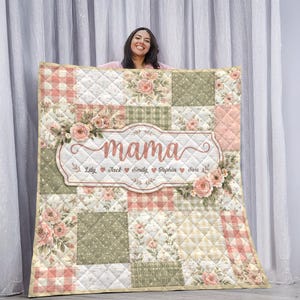 May include: A patchwork quilt in pastel shades of pink, green, and cream. The quilt is personalized with the word "mama" in a decorative frame, and names. Floral accents and a quilted pattern are also visible.
