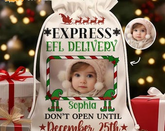 May include: A white drawstring Christmas gift bag with a photo of a baby wearing a pink hat. The bag has the text "EXPRESS EFL DELIVERY" and "DON'T OPEN UNTIL December 25th". A red sleigh and reindeer graphic is at the top.