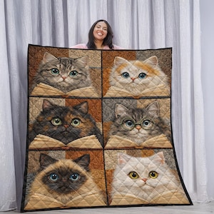 May include: A quilted blanket featuring six cat portraits, each with a different coat color and eye color, reading books. The cats are set against a patchwork background of brown and tan squares. The blanket is held up by a person.