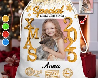 May include: White Christmas gift bag with gold text and accents. The bag features a photo of a girl holding a rabbit, the name "Anna", and the text "Special Delivery For Xmas 2025". Includes North Pole stamps and the text "Do Not Open Before 25 December".