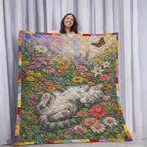 May include: A colorful quilt featuring a cat lying in a field of flowers. The quilt has a vibrant floral design with a butterfly and a border of various colors. The cat is gray and white, and the flowers are in shades of pink, yellow, and purple.