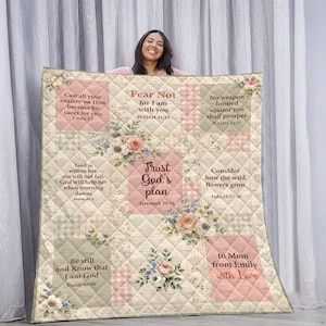 Può includere: Una trapunta beige e rosa con decorazioni floreali e citazioni ispiratrici. La trapunta presenta testi come "Non temere", "Abbi fiducia nel piano di Dio" e "a mamma da Emily con amore".
