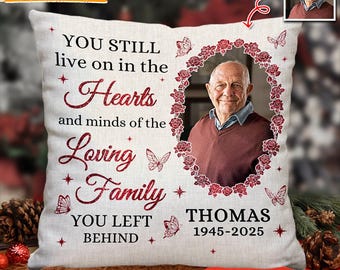Op de afbeelding: Een gepersonaliseerd herdenkingskussen met een foto van een man omringd door een bloemenkrans. Het kussen heeft de tekst "YOU STILL live on in the Hearts and minds of the Loving Family YOU LEFT BEHIND" en de naam "THOMAS 1945-2025".