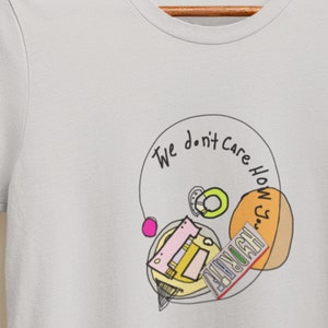 May include: A light gray t-shirt with a circular design featuring a cassette tape, a yellow and orange circle, and a green ring. The text "We don't care how you" is written around the circle.