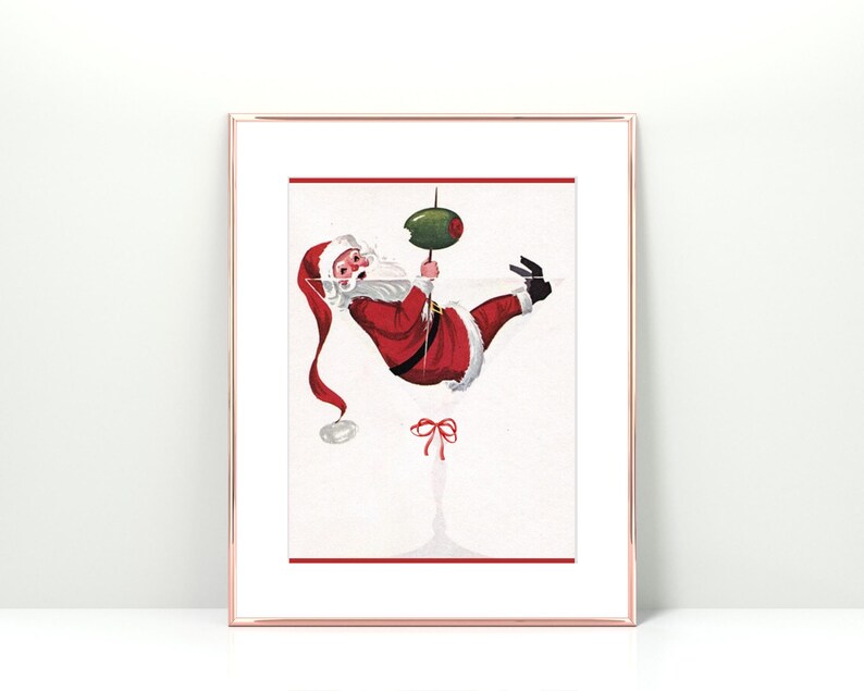 Op de afbeelding: Een vintage kerst-illustratie van Sinterklaas die ondersteboven hangt in een martini-glas met een olijf. De illustratie is in een wit frame met een gouden rand.