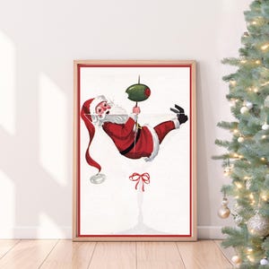 Op de afbeelding: Een vintage kerst-illustratie van Sinterklaas die ondersteboven hangt in een martini-glas met een olijfje als garnering. De illustratie is in een rood-wit-groen kleurenschema.