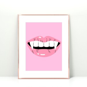 May include: A pink framed print with a pink cartoon mouth with fangs. The background is pink.