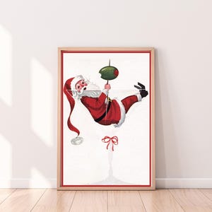 Op de afbeelding: Een vintage kerst-illustratie van Sinterklaas die ondersteboven hangt in een martini-glas met een olijfje als garnering. Het glas is rood en wit met een groene olijf.