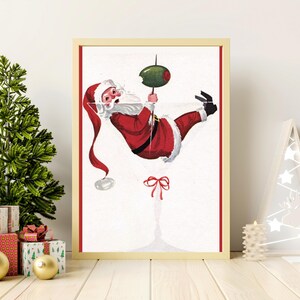Op de afbeelding: Een vintage kerst-illustratie van Sinterklaas die aan een martini-glas hangt met een olijf. De illustratie is in een rood-wit-groen kleurenschema.
