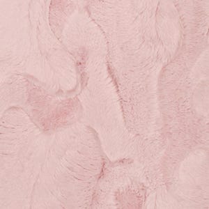 May include: A close-up view of a soft, pink faux fur fabric. The plush material has a wavy, textured pattern, creating a luxurious appearance. The light pink colour adds a touch of elegance and warmth, suitable for various textile projects.