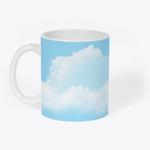 May include: White ceramic mug featuring a blue sky and white cloud design.
