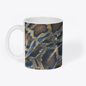 May include: A white ceramic mug with a close-up image of a python's skin. The skin is a mix of brown, black, and blue colors.