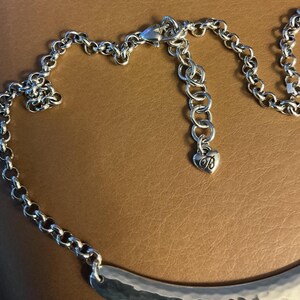 Puede incluir: Collar plateado con un colgante de metal martillado. El collar presenta una cadena con un cierre de mosquet&oacute;n y una extensi&oacute;n ajustable. Un peque&ntilde;o dije en forma de coraz&oacute;n con la letra "B" cuelga de la extensi&oacute;n.