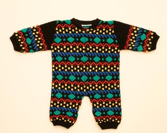 May include: A black knitted baby onesie with a colorful geometric pattern in red, yellow, blue, and green.