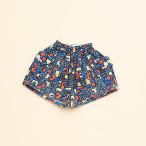May include: Blue, red and yellow patterned shorts with an elastic waistband and a single button on the side.