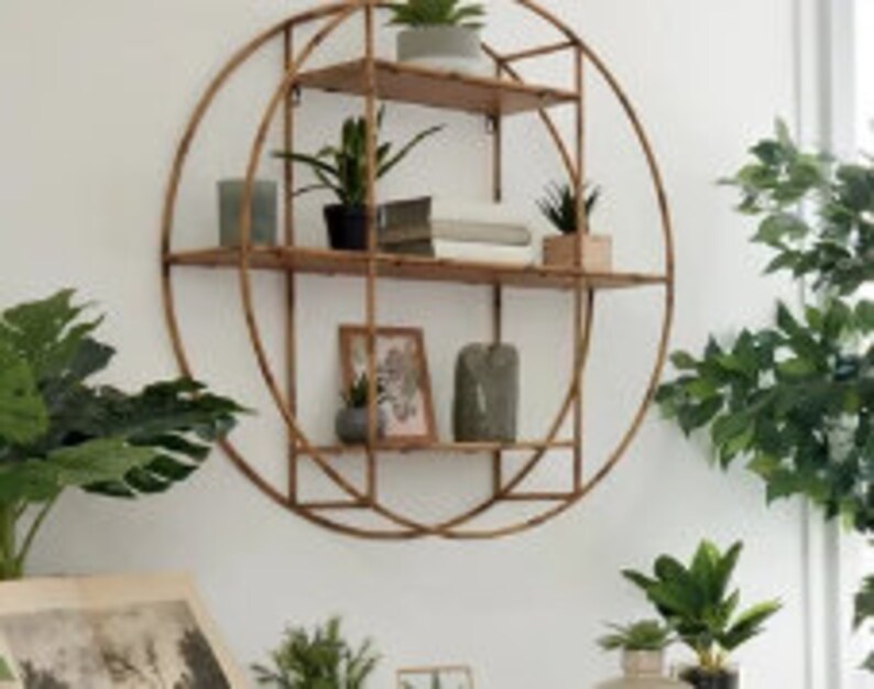 May include: A round, gold metal wall shelf with three wooden shelves. The shelf is decorated with plants and books.