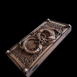 Puede incluir: Una caja de madera marrón con un detallado relieve de un dragón. El dragón está centrado en la tapa, rodeado de patrones ornamentados. La caja tiene esquinas redondeadas y un cierre.