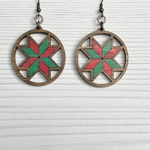 Può includere: Un paio di orecchini in legno con un design a stella rosso e verde. Gli orecchini sono rotondi e hanno un design ritagliato.
