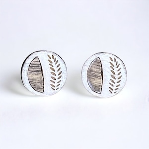 May include: A pair of white wooden earrings with a brown wood grain design. Each earring features a half circle and a leaf pattern.