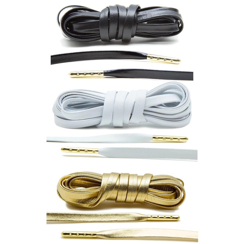 May include: Four pairs of shoelaces in different colors: black, white, light blue, and gold. The laces are made of leather and have gold metal aglets.