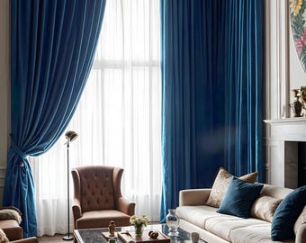 May include: A living room with a white couch and blue velvet curtains. The couch has several pillows and a glass coffee table in front of it. There is a brown leather armchair to the left of the couch.
