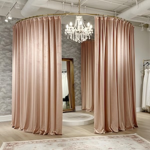May include: A pink velvet curtain backdrop with a gold metal rod and a crystal chandelier hanging from the ceiling. The backdrop is in a room with a white tiled floor and a rug.