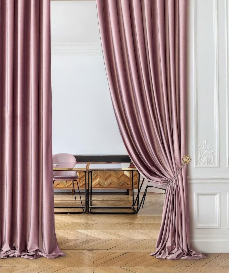 Double-sided luxe velvet divider curtains in warm taupe-brown tones, hung on black curved metal rod. Elegant room divider drapes with rope tiebacks and tassels, featuring sophisticated pleats and full floor-length drape. Customizable luxury curtain panels ideal for archway entrances, bedroom partition, or creating separate room spaces. High-end interior design window treatment with rich velvet texture. Professional home decor solution for modern and classical interiors.