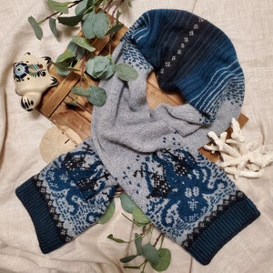 May include: A grey and blue knitted scarf with an octopus pattern. The scarf is folded in half and has a fringe on the ends.