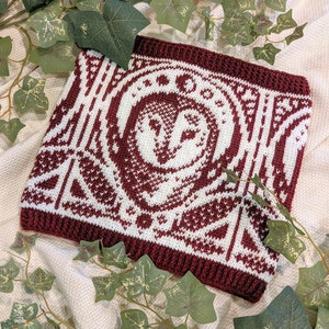 May include: A crocheted square with a white owl design on a burgundy background. The square is surrounded by a burgundy border.