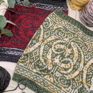 Pode incluir: Dois quadrados de malha, um vermelho com um padrão preto e branco e outro verde com um padrão amarelo e branco. Os quadrados estão sobre uma superfície bege com novelos de lã e folhas verdes.