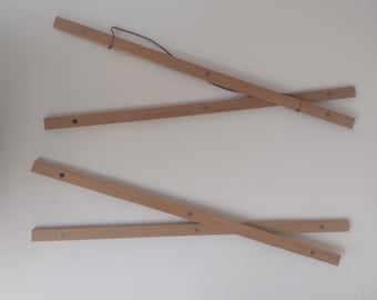 May include: Four wooden rods with metal connectors, forming a cross shape. The rods are light brown and have a natural finish. The connectors are silver and are located at the ends of the rods.
